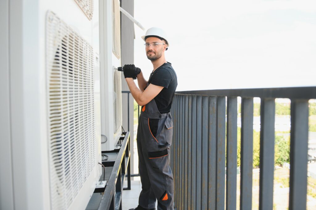 Young man repairman checking an outside air conditioner unit